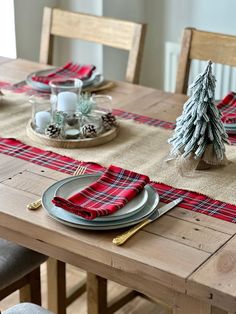 the table is set for christmas dinner with plaid napkins and place mats on it