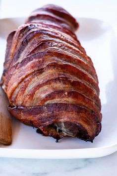 sliced bacon on a white plate with a wooden spoon