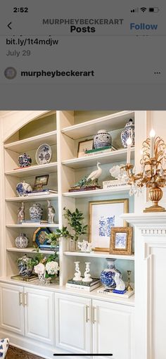 a white bookcase with blue and white china on the top shelf next to a fireplace