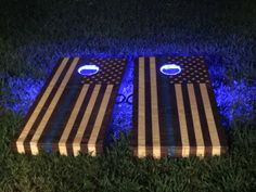 two wooden boards with american flags on them are lit up in the grass at night