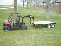 a red utility vehicle pulling a trailer on the grass