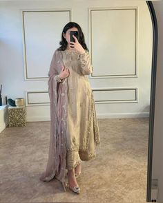 a woman taking a selfie with her cell phone in a room that has white walls and beige carpet