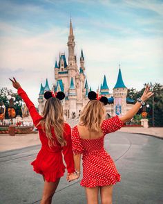 two girls in front of a castle wearing minnie mouse ears and red polka dot dresses