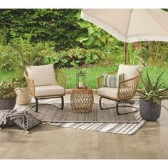 a patio with two chairs and an umbrella on the ground in front of some plants