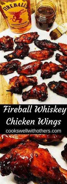 chicken wings are sitting on a cutting board next to a jar of fireball whiskey