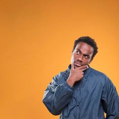 a man in a blue shirt is posing for the camera with his hand on his chin