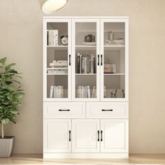 a white bookcase with glass doors next to a potted plant on the floor