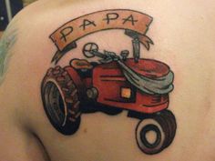 a tattoo on the back of a woman's shoulder with a tractor and banner