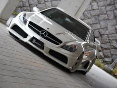 a white sports car parked in front of a stone wall