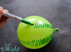 a person is writing on an inflatable ball with a green marker and pen