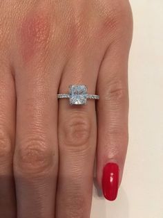 a woman's hand with a ring on it and a red manicured nail