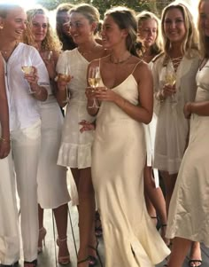 a group of women standing next to each other holding wine glasses