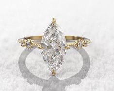 an oval cut diamond ring with three small diamonds on the band and side stones in yellow gold