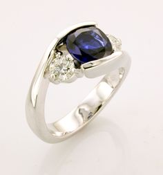 a blue and white diamond ring with two diamonds on the side, set in 18k white gold