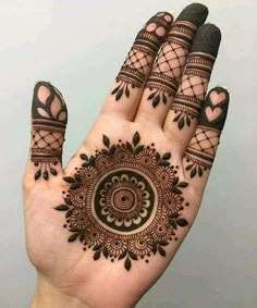 a hand with henna tattoos on it and an intricate circular design in the middle