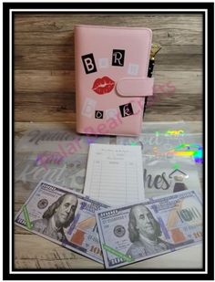 a pink purse with money and notes on it next to a notepad, pen and notebook