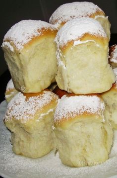 a white plate topped with lots of powdered sugar covered pastries on top of each other