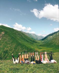 a group of people laying on top of a lush green hillside