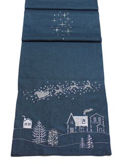 a tea towel with a santa's sleigh flying over houses and trees