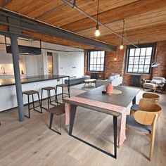 an open concept kitchen and living room with hardwood floors, exposed ceilings, white walls, and wooden flooring