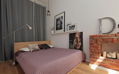 a bed sitting next to a brick fireplace in a room with pictures on the wall