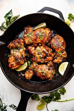 chicken in a skillet with limes and cilantro