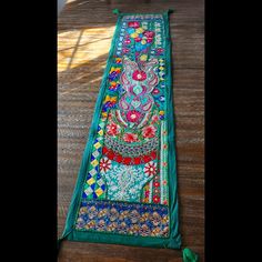 a long piece of cloth with colorful designs on it sitting on top of a wooden floor