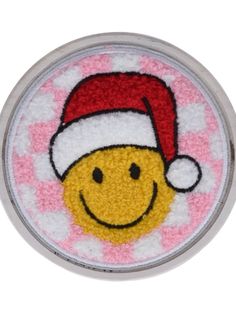 a smiley face wearing a santa hat on top of a white and pink circular object