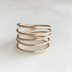 "This beautiful minimalist adjustable coil ring looks like stacked rings! Handmade by wire wrapping shiny, beautiful gold filled wire into an adjustable coil. Easily adjustable to any size finger. DETAILS *Color: Gold *Handmade from 20 gauge 14k gold filled wire sourced in the USA. *Wire wrapped and hammered for added strength. ADDITIONAL COLORS AVAILABLE Love these but want them in a different color? We have rose-gold and sterling silver coil rings available. Follow the link below to find your Minimalist 14k Gold Spiral Ring, Gold Spiral Minimalist Stackable Rings, Gold Spiral Stackable Rings, Gold Minimalist Wire Wrapped Stackable Rings, Minimalist Gold Wire Wrapped Stackable Rings, Minimalist 14k Gold Wire Wrapped Rings, Gold Minimalist Wire Wrapped Midi Rings, Minimalist Rose Gold Wire Wrapped Ring, Gold Wire Wrapped Minimalist Midi Rings