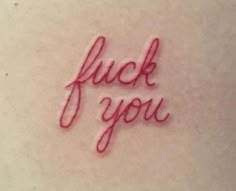 the word fluck you written in red ink on a woman's back stomach