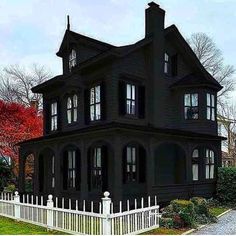 a large black house with white picket fence