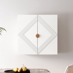 a table with two pears on it next to a white wall and a clock