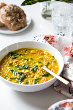 a bowl of soup with spinach and other foods on the table next to it