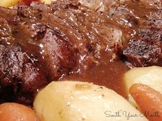 a close up of some meat and potatoes on a plate with gravy in the middle