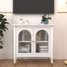 a white cabinet with two glass doors in front of a flat screen tv