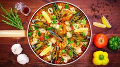 a bowl filled with pasta and vegetables on top of a wooden table next to garlic