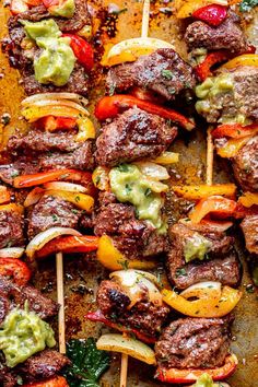 the skewers are covered with meat, peppers and guacamole sauce