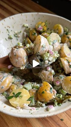 a white bowl filled with potato salad on top of a wooden table