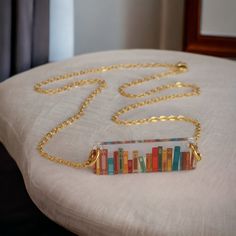 This handmade necklace is in the shape of a bar but with books on a shelf patterned acrylic that matches our popular earrings now in a bar necklace form! This necklace measures 18 inches long with a stainless cable steel chain and lobster claw clasp that will not tarnish and is hypoallergenic. Lightweight too! -- Choice of chain color:    - GOLD    - SILVER Bar pendant measures 3/8 inch by 1 3/8 inch and is made from 1/8th thick clear cast acrylic that is UV printed with the pattern of bookcases Bookshelf Bar, Popular Earrings, Book Necklace, Resin Jewelry Diy, Steel Chain, Bar Pendant, Everyday Necklace, Silver Bars, Bar Necklace