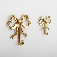 two gold colored metal items on a white surface, one is shaped like an elephant and the other has a bow