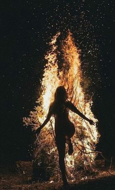 a woman standing in front of a fire