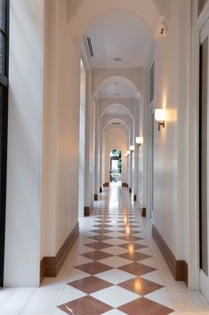 the hallway is lined with white and brown checkered flooring, along with two lamps on either side