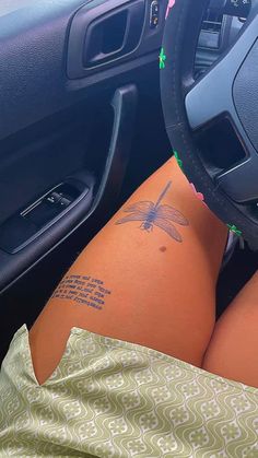 a person with a tattoo on their thigh sitting in a car