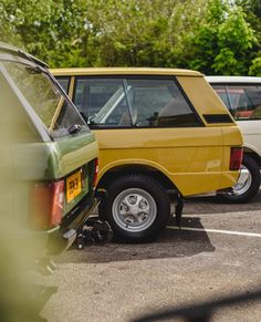 several cars parked in a parking lot with trees in the backgrounds