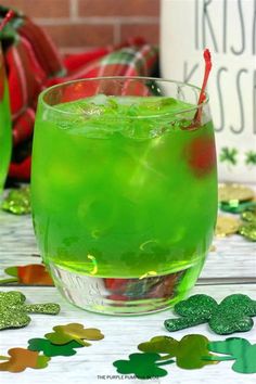 a green drink sitting on top of a table next to confetti and shamrocks