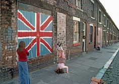 two children are playing on the sidewalk in front of a building with a union jack flag painted on it