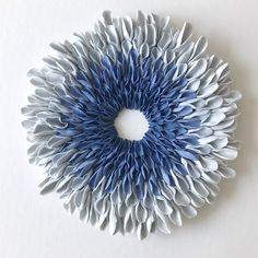 a blue and white paper flower on a white surface