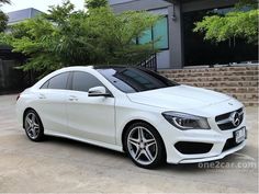 a white mercedes cla is parked in front of a building with steps leading up to it