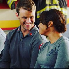 a man and woman sitting next to each other in front of a firetruck