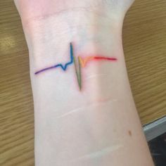 a small heartbeat tattoo on the wrist with an orange and green line going through it